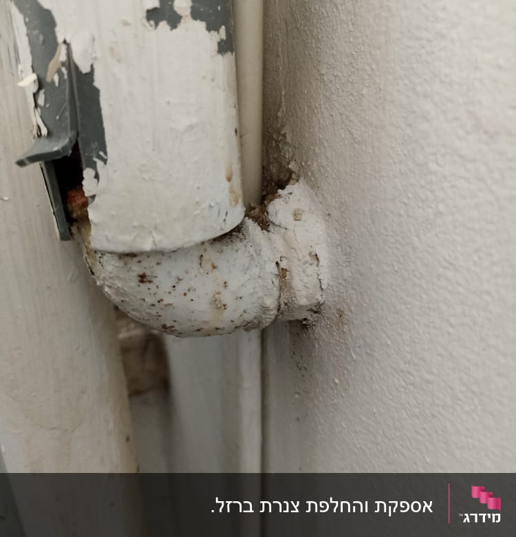 צינור מתכת חלוד עם חיבור לקיר
